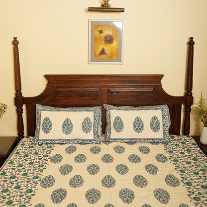 Bed with floral bedding and pillows, wooden headboard, and framed artwork on wall.