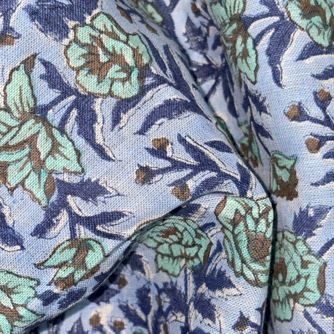 Close-up of floral fabric with blue, green, and brown colors.