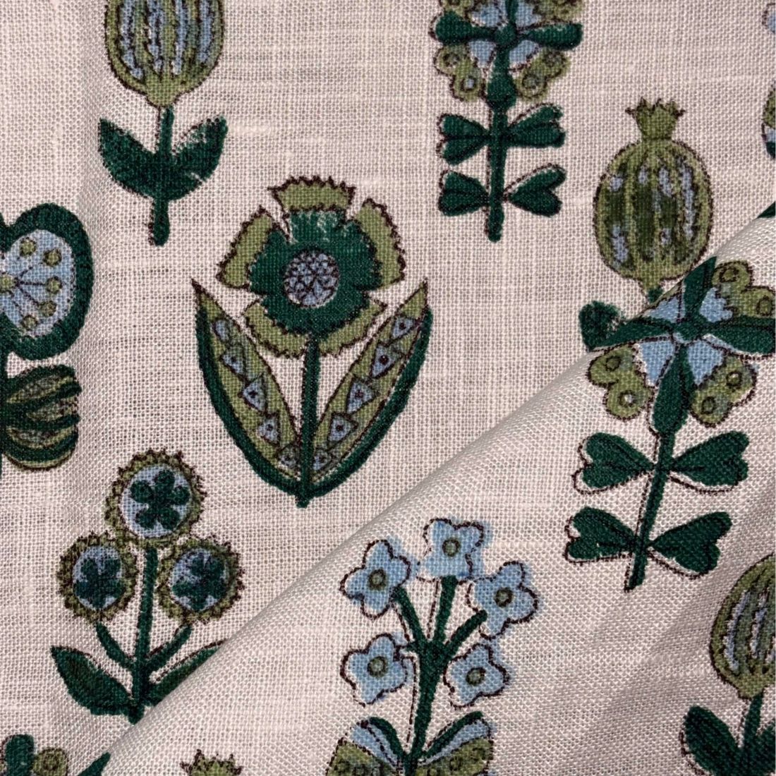 Close-up of floral patterned fabric with green and blue flowers on a grey background
