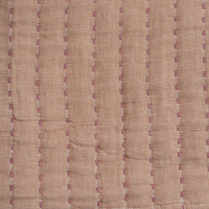 Close-up of beige throw with purple stitching