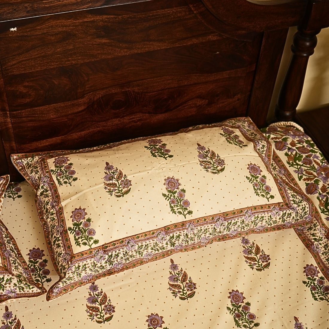 Floral-patterned pillow and bedspread on a wooden bed