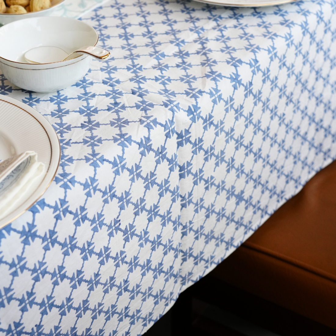Blue and white patterned tablecloth on a dining table with plates and bowls.