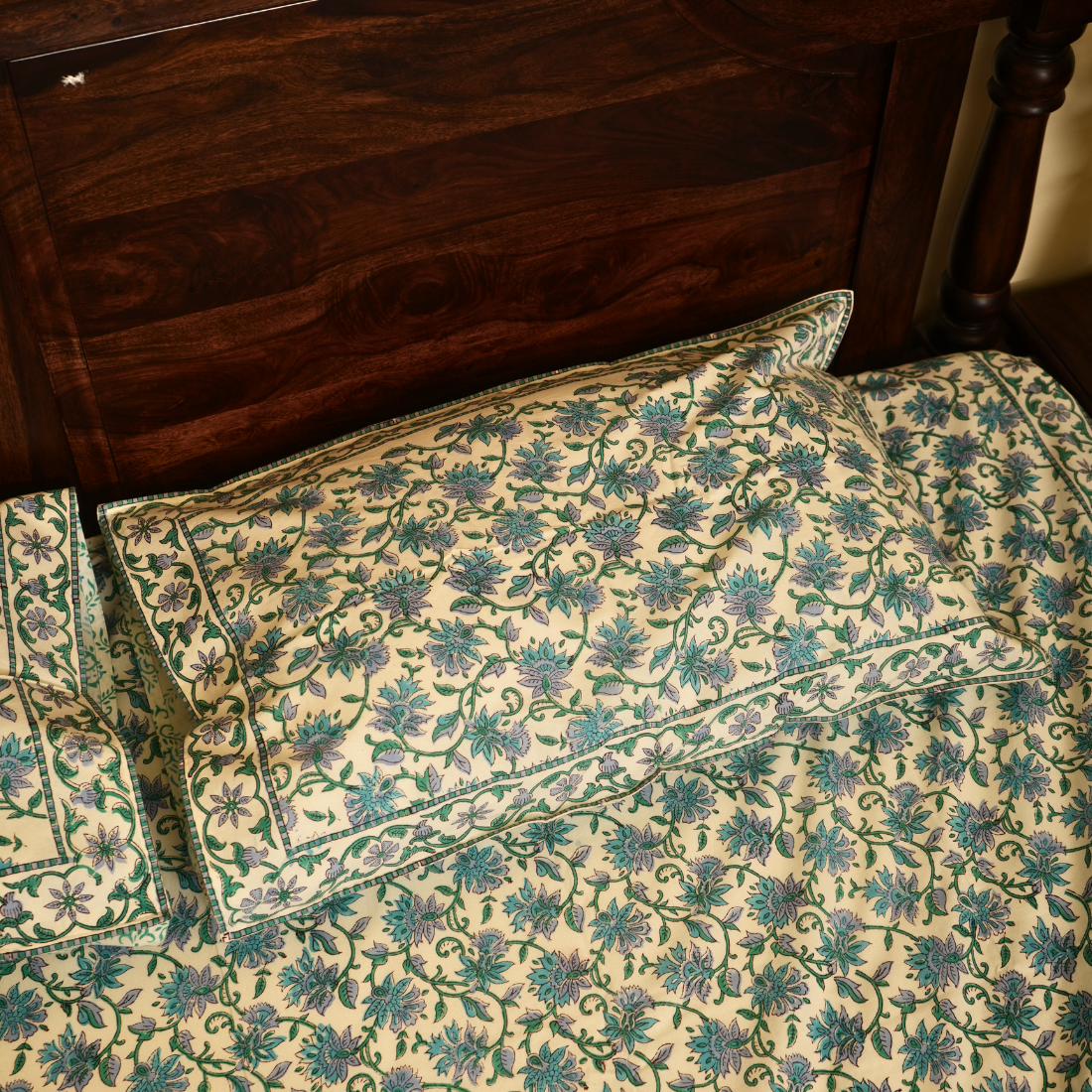 Floral patterned pillows on a bed with wooden headboard