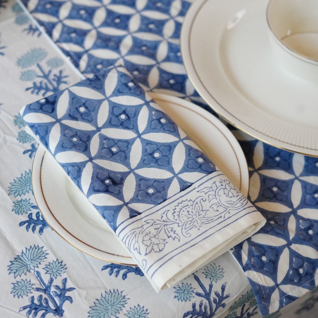 Blue and white patterned tablecloth with folded napkin on a table setting.