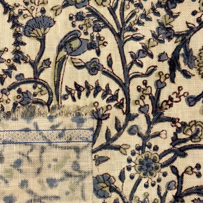 Close-up of floral patterned fabric with blue and green colors on a beige background.