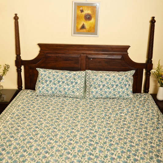 Floral-patterned bedspread on a wooden bed with a decorative headboard.