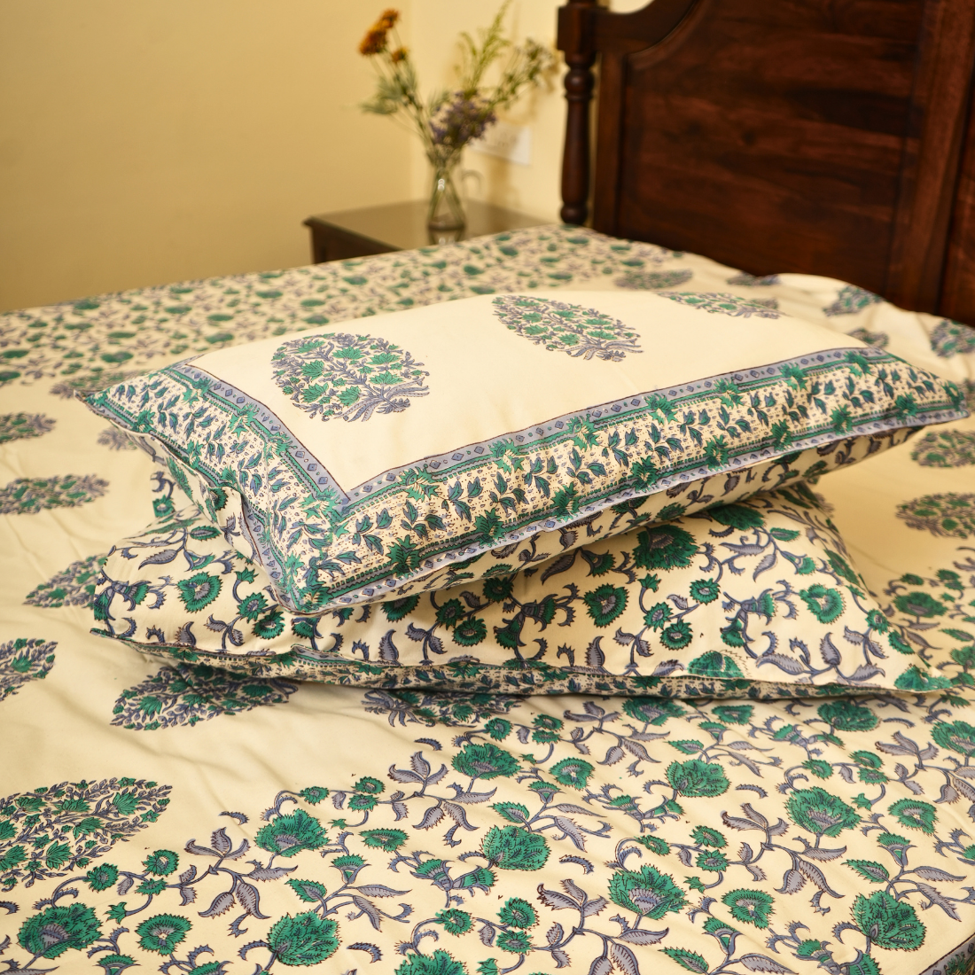 Floral patterned bedding set on a bed with a wooden headboard.