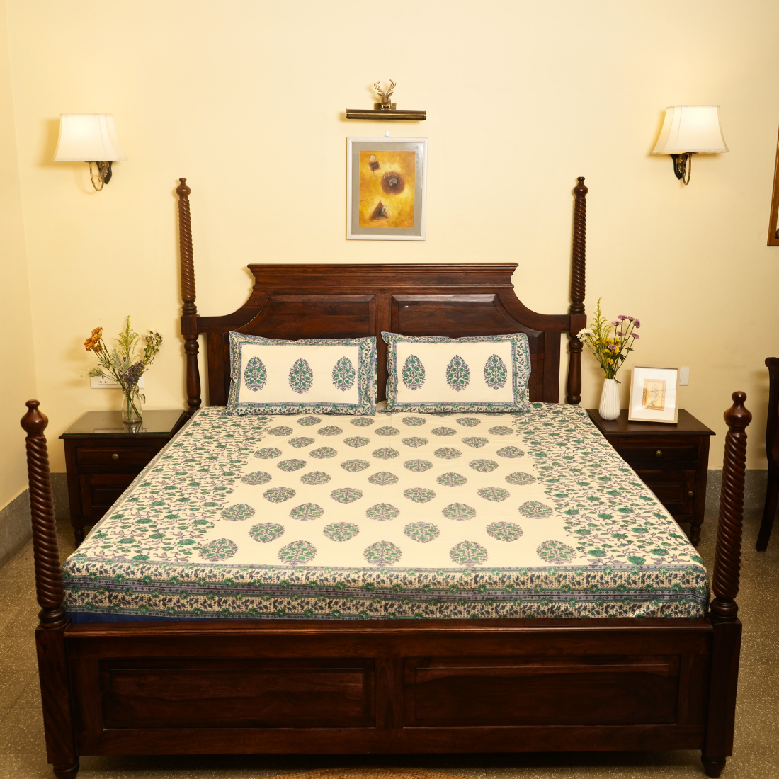 Bedroom with a wooden bed and floral bedding, two nightstands with lamps and decor.