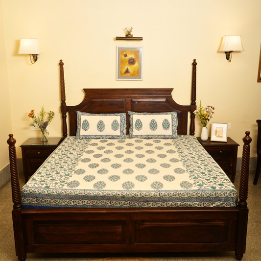 Bedroom with a wooden bed and floral bedding, two nightstands with lamps and decor.