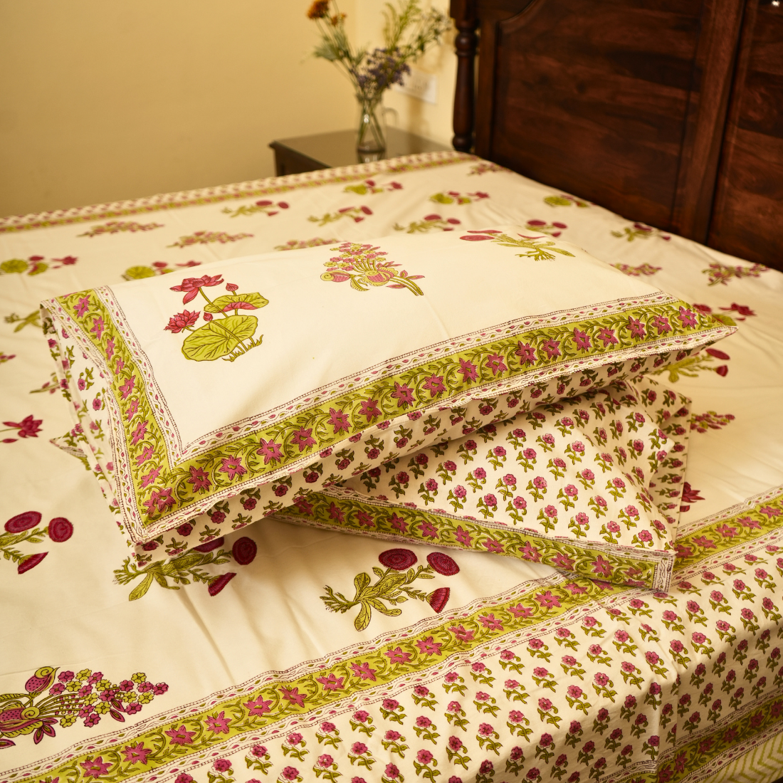 Floral patterned pillows on a bed with a wooden headboard.