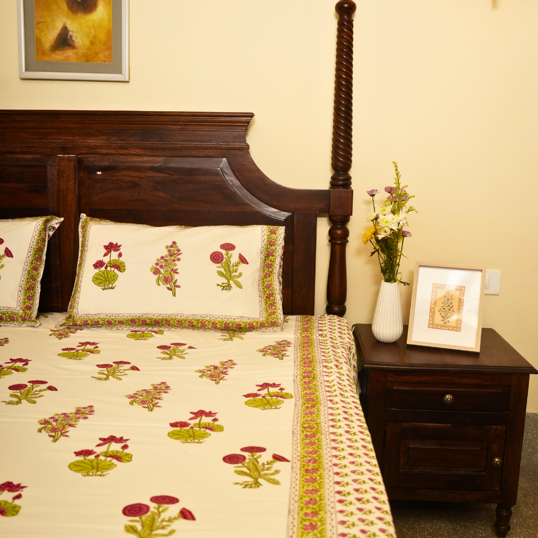 Bedroom with floral bedspread, wooden headboard, and nightstand with decorative items.