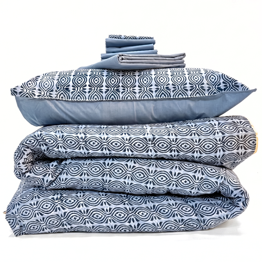 Stack of blue and white patterned bedding on a white background