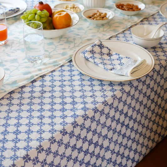 Dining table with a patterned tablecloth, plates, and fruit