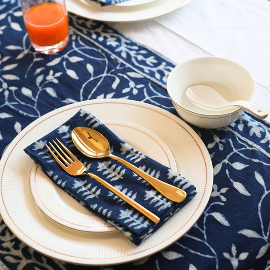 Table setting with gold cutlery on a blue patterned tablecloth