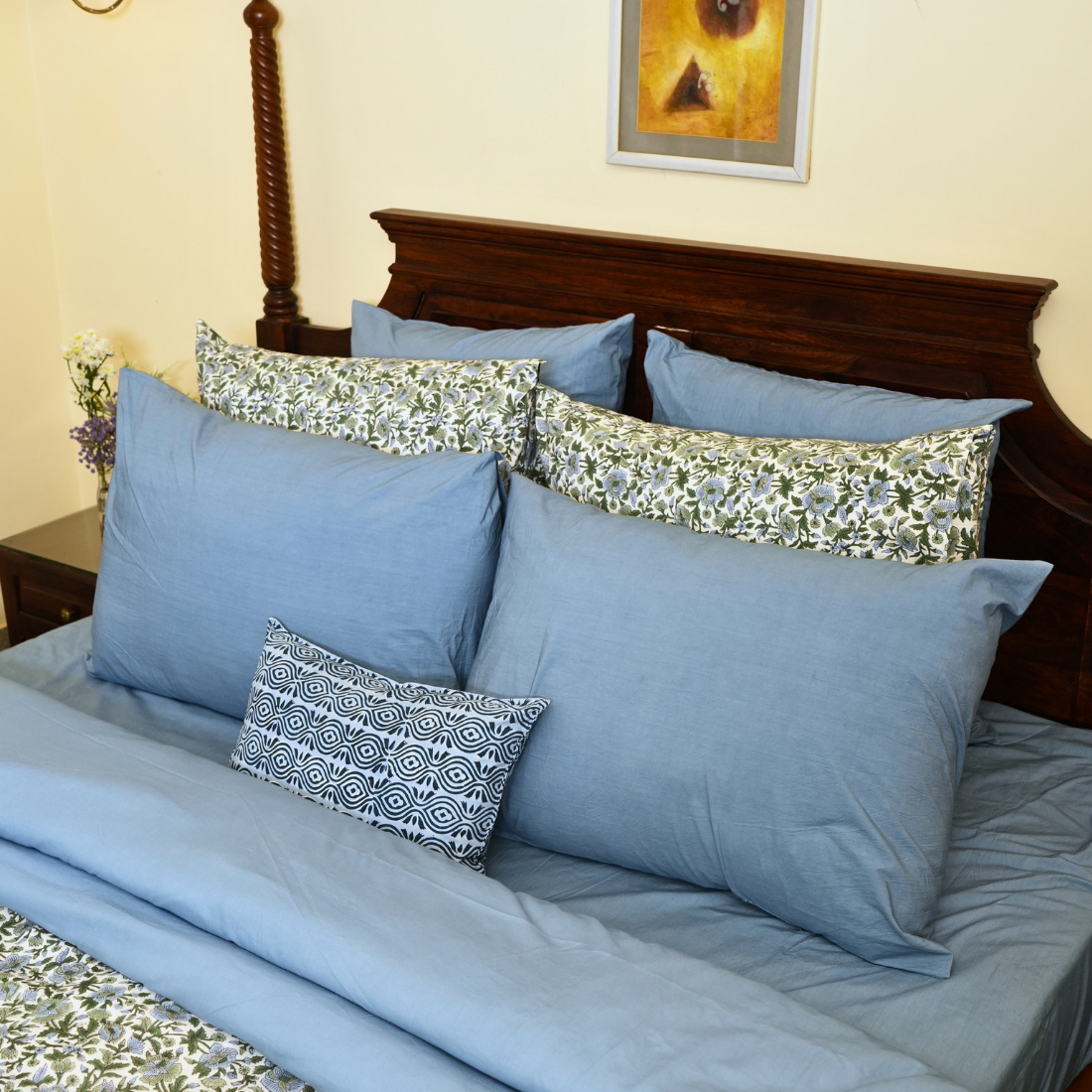 Bed with blue bedding and decorative pillows in a bedroom setting.