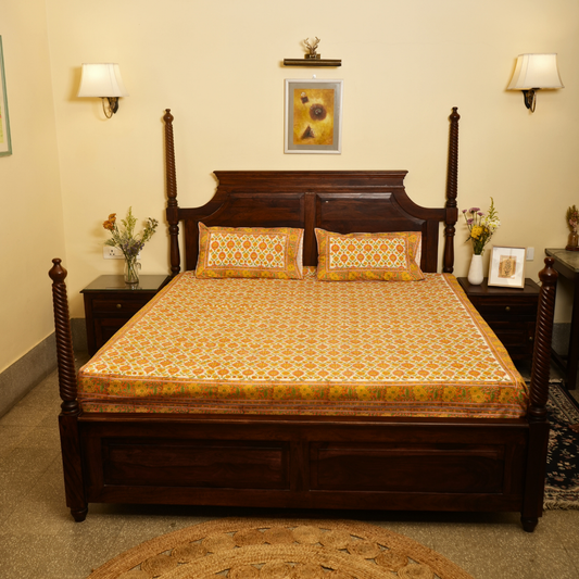 Wooden bed with patterned bedding in a room with lamps and decor.