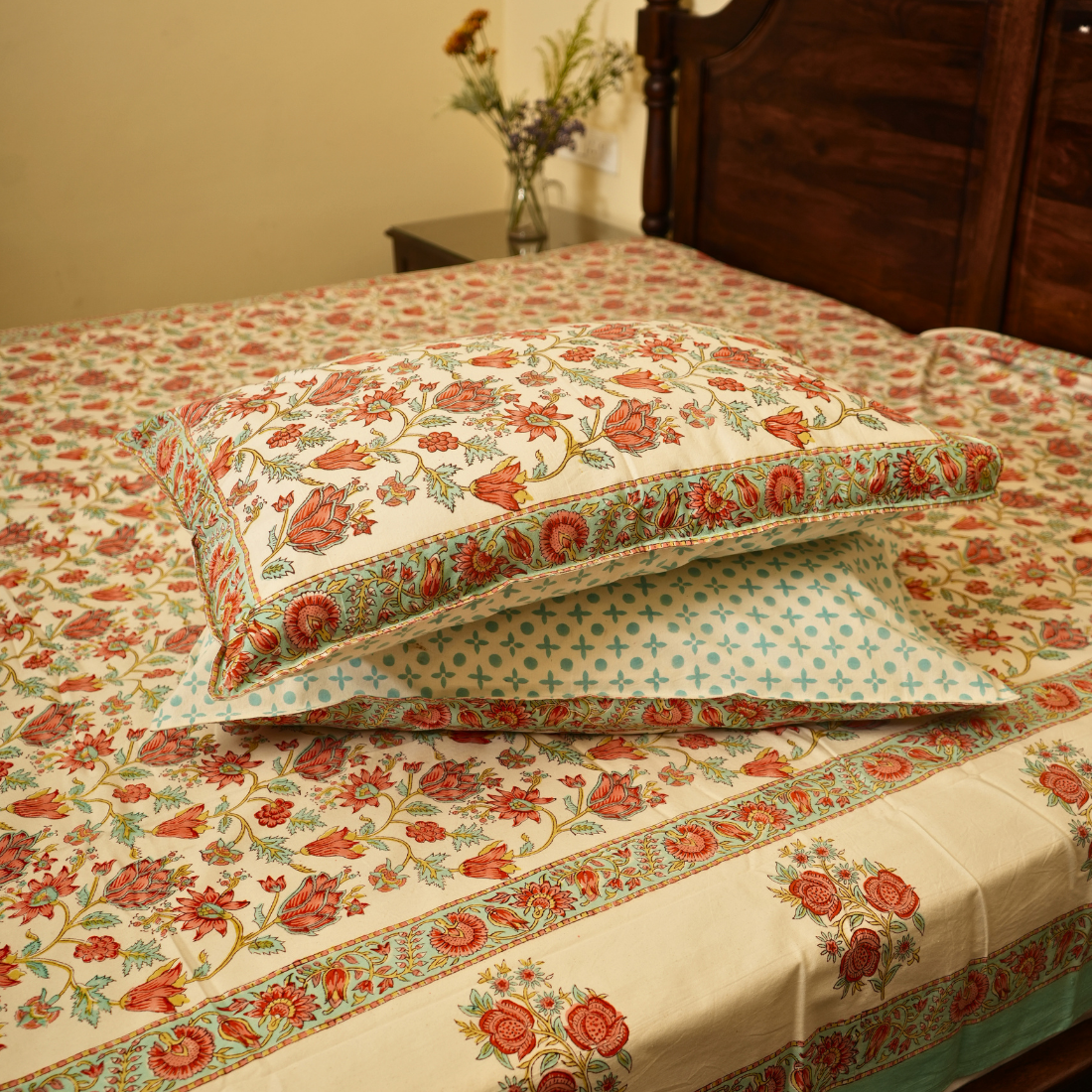 Floral patterned bedding set on a bed with a wooden headboard.