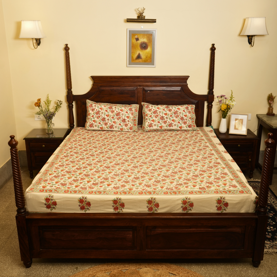 Bedroom with a wooden bed and floral bedding, two nightstands with lamps and decor.
