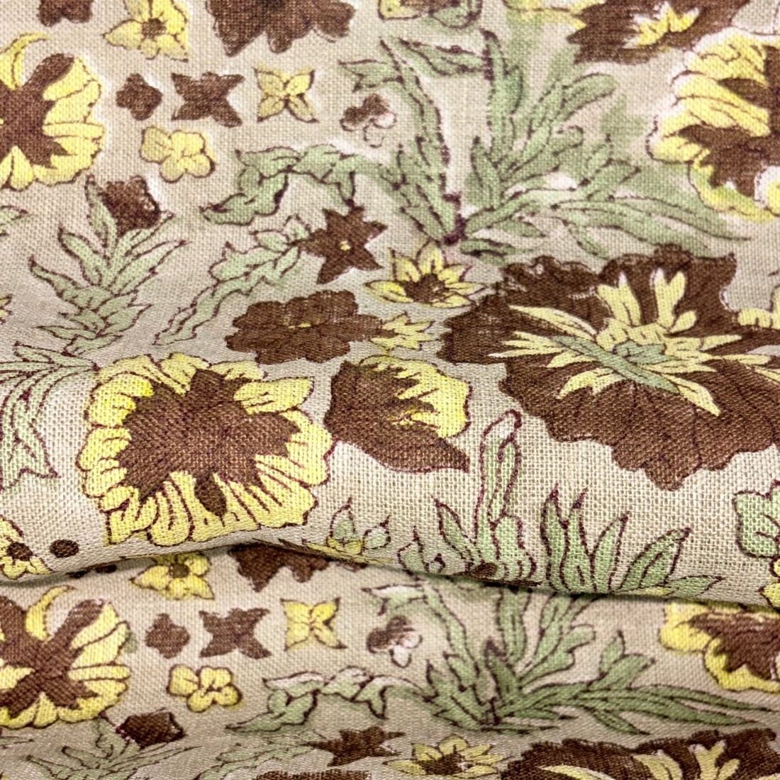 Close-up of floral fabric with brown, yellow, and green colors on a grey background.