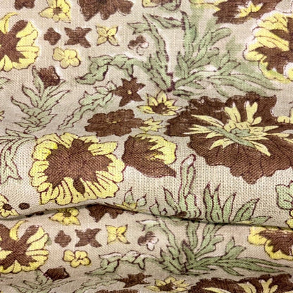 Close-up of floral fabric with brown, yellow, and green colors on a grey background.