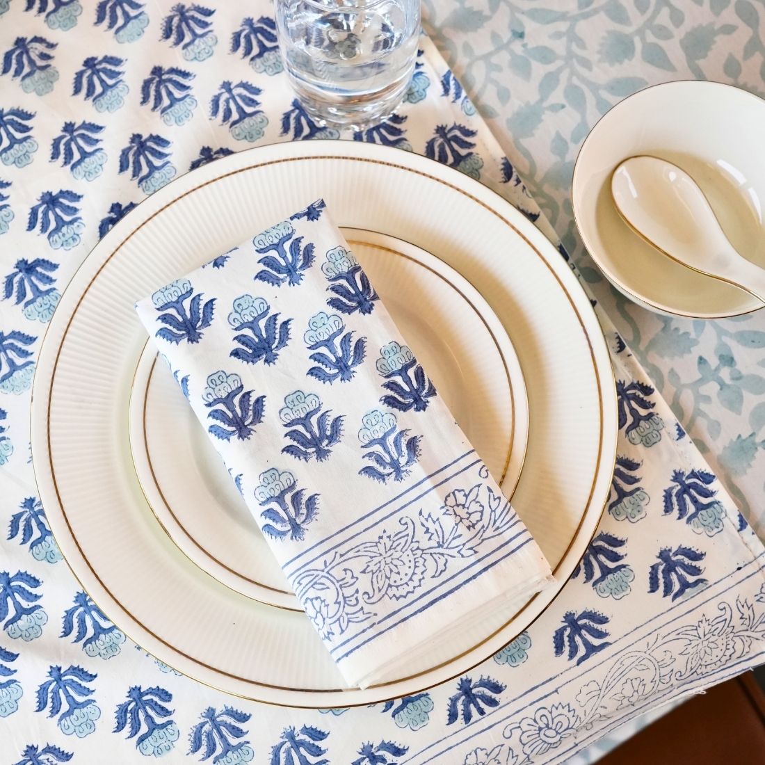 Table setting with blue and white patterned tablecloth, plates, and napkin.