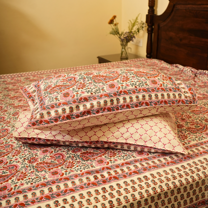 Patterned pillows on a bed with a wooden headboard and side table in the background.