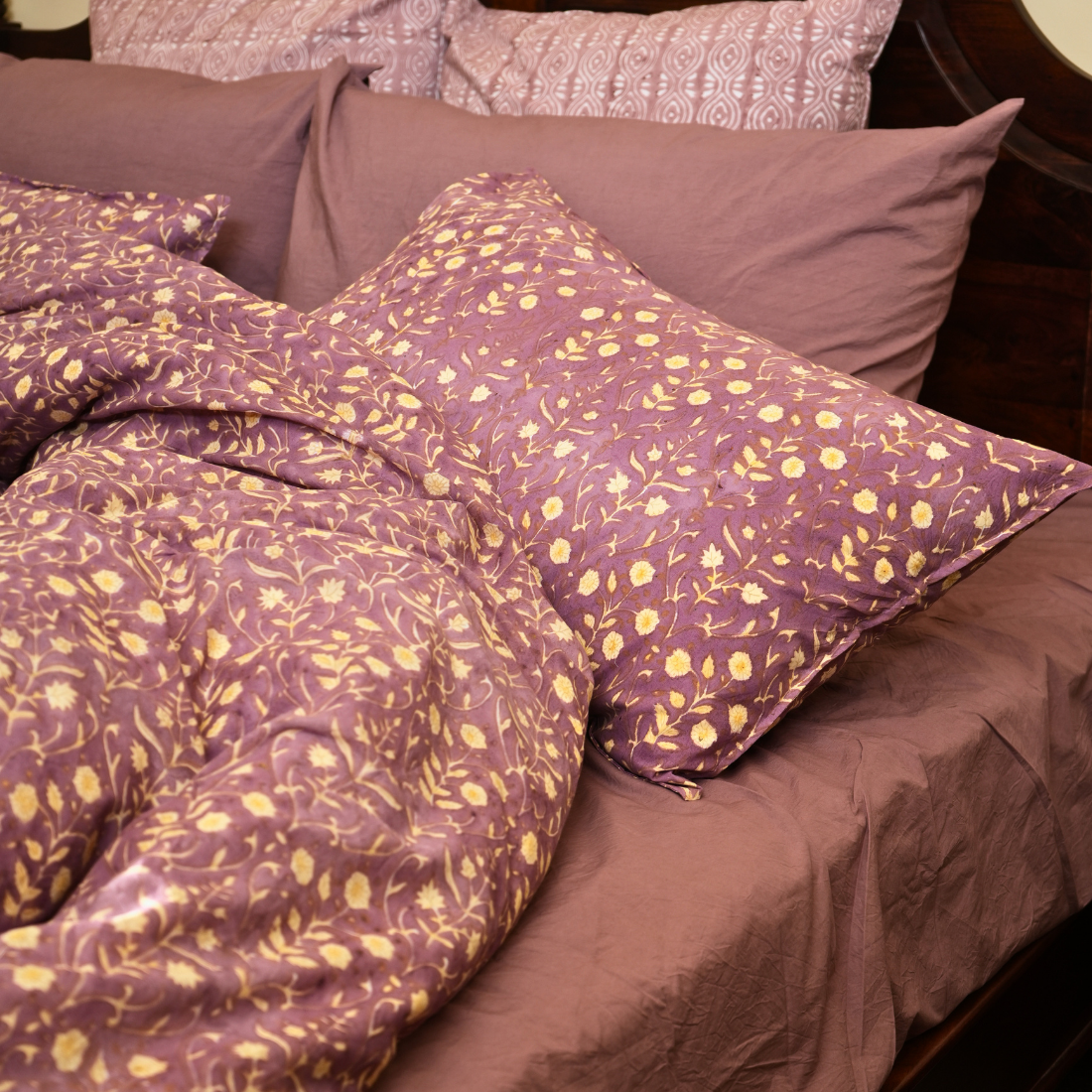 Purple floral bedding with matching pillows on a bed.