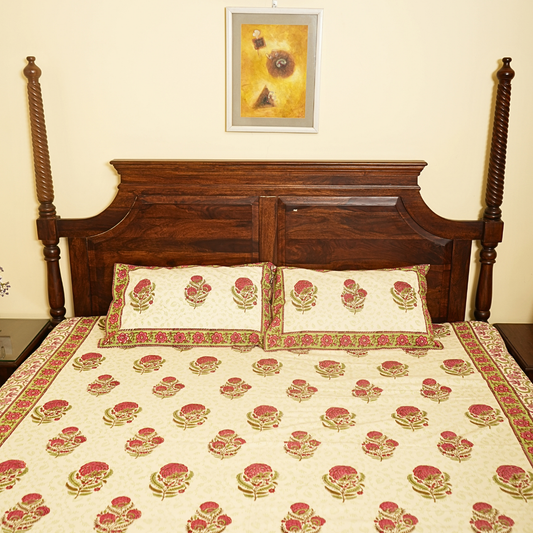 Wooden bed with floral bedding and a framed picture on the wall.