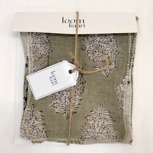 A folded fabric sample or textile piece with a botanical damask pattern in muted olive green and beige, packaged with a white paper header card and a small white tag tied with twine.