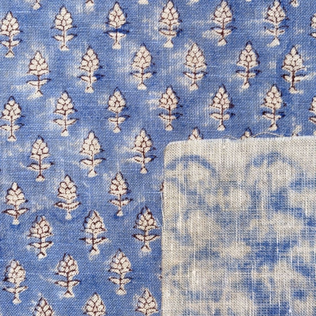 Blue fabric with white floral pattern and a folded white square.