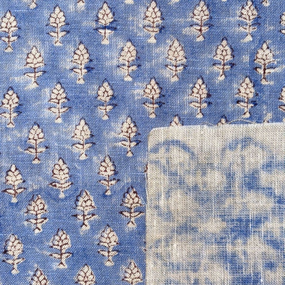 Blue fabric with white floral pattern and a folded white square.
