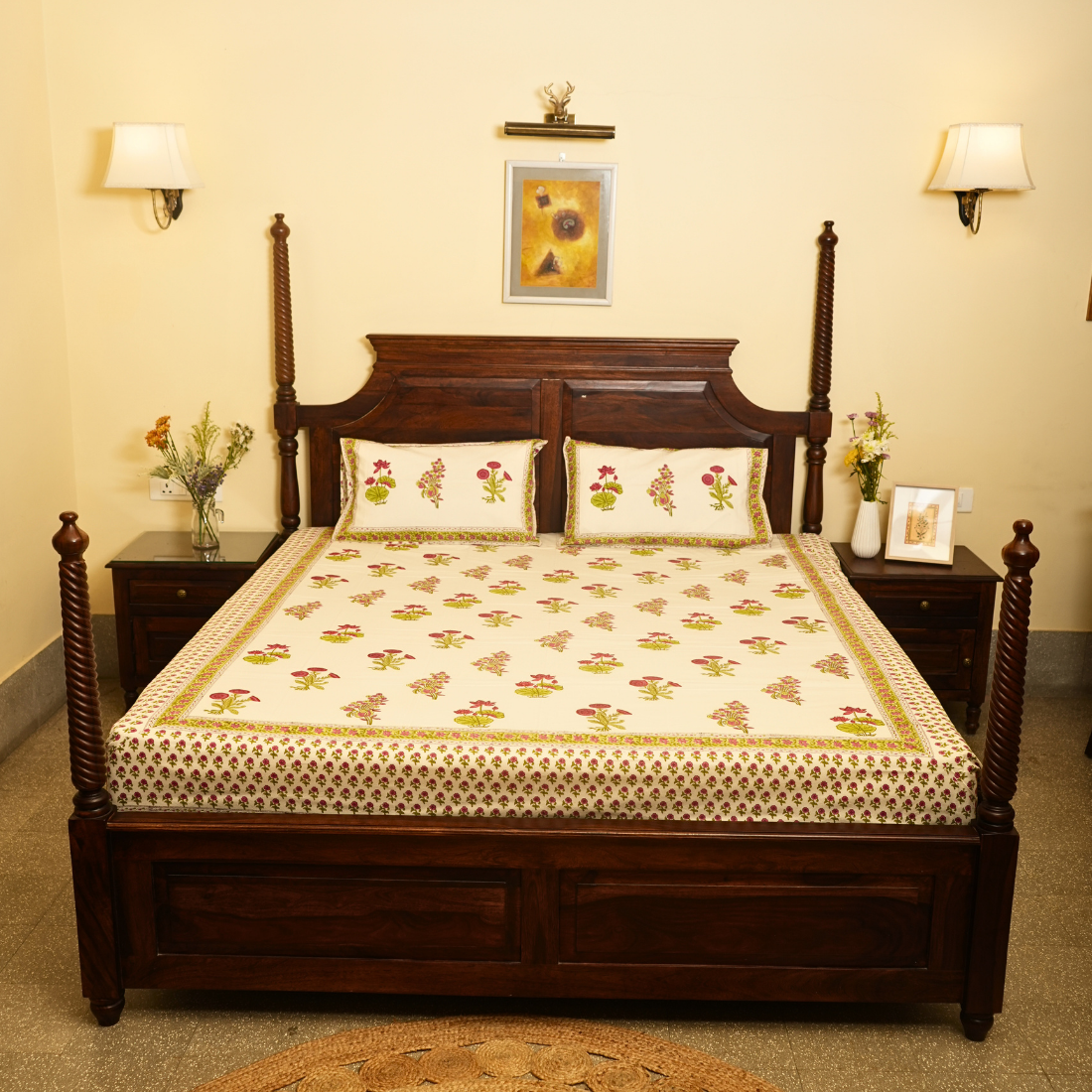 Bedroom with a wooden bed and floral bedding, two nightstands with lamps and decor.