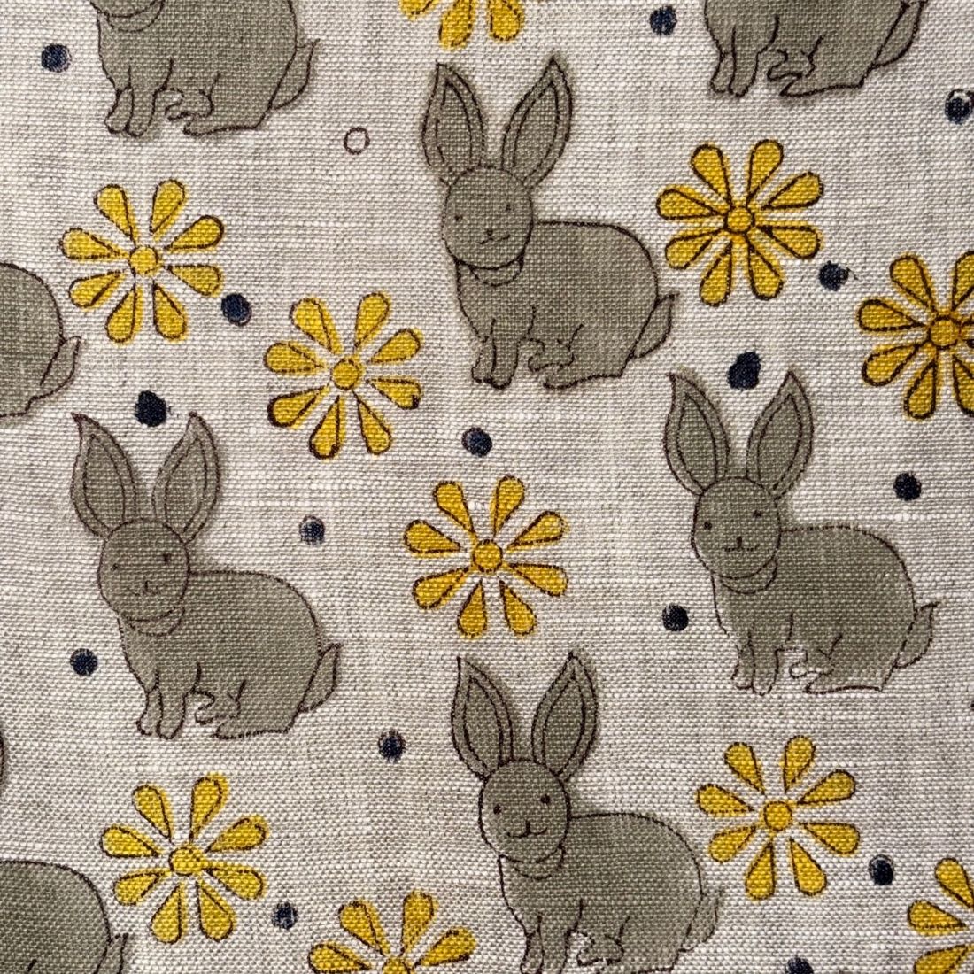 Fabric with gray rabbits and yellow flowers on a grey background