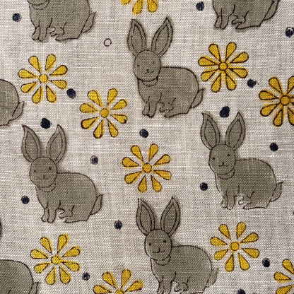 Fabric with gray rabbits and yellow flowers on a grey background