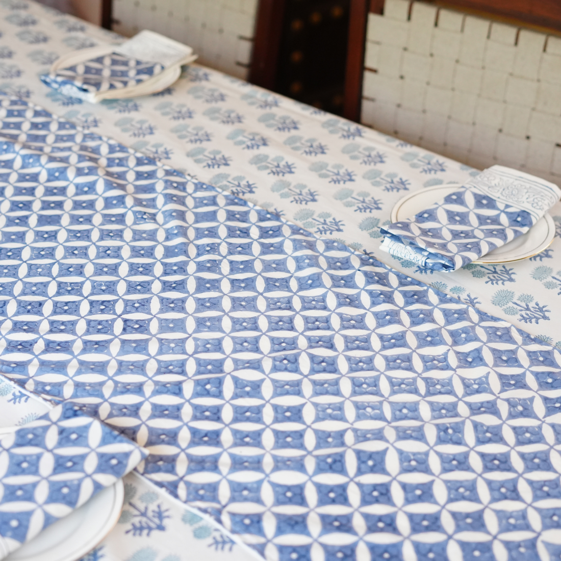 Blue and white patterned table linen set on a dining table with chairs.