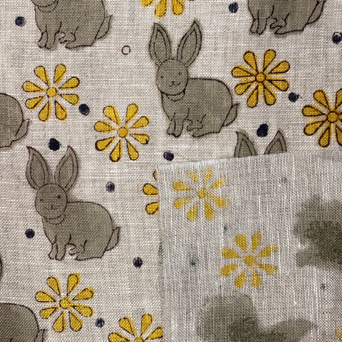 Fabric with embroidered bunnies and flowers on a grey background