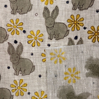 Fabric with embroidered bunnies and flowers on a grey background