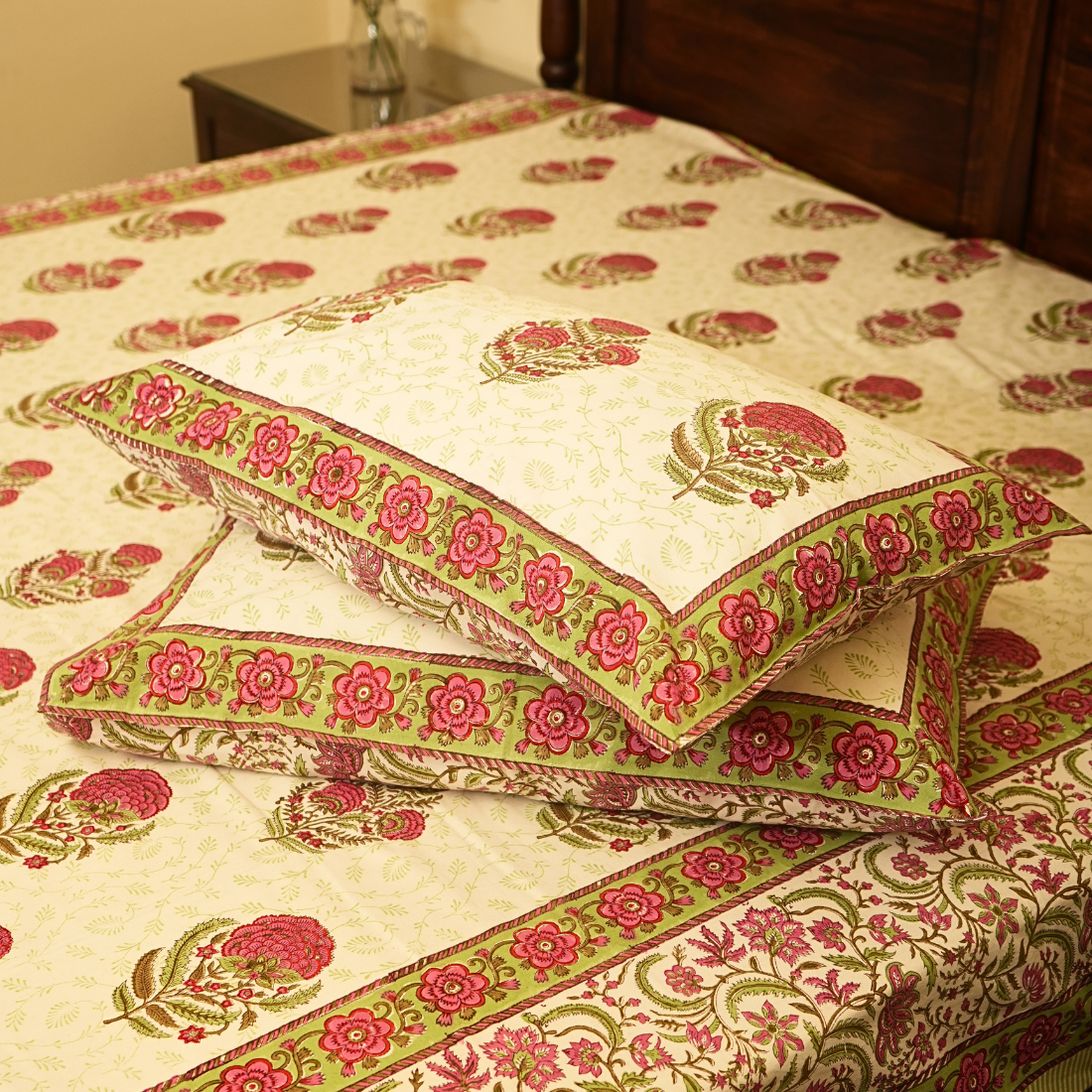 Floral patterned bedspread with matching pillows on a bed.
