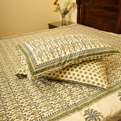Decorative pillows with floral patterns on a bedspread in a bedroom setting.