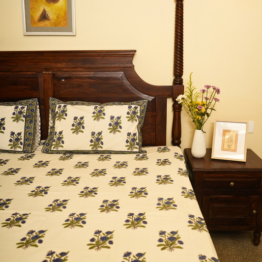 Bedroom with floral bedspread, wooden headboard, and side table.