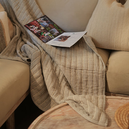 Beige blanket draped over a beige sofa with a magazine on top