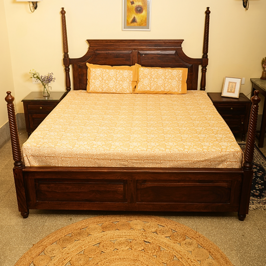 Wooden bed with floral bedding and pillows in a bedroom setting.