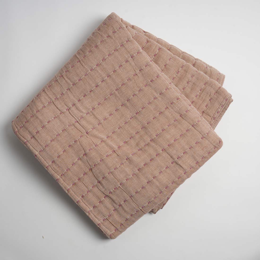 Folded beige throw on a light gray background