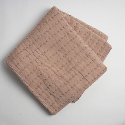 Folded beige throw on a light gray background