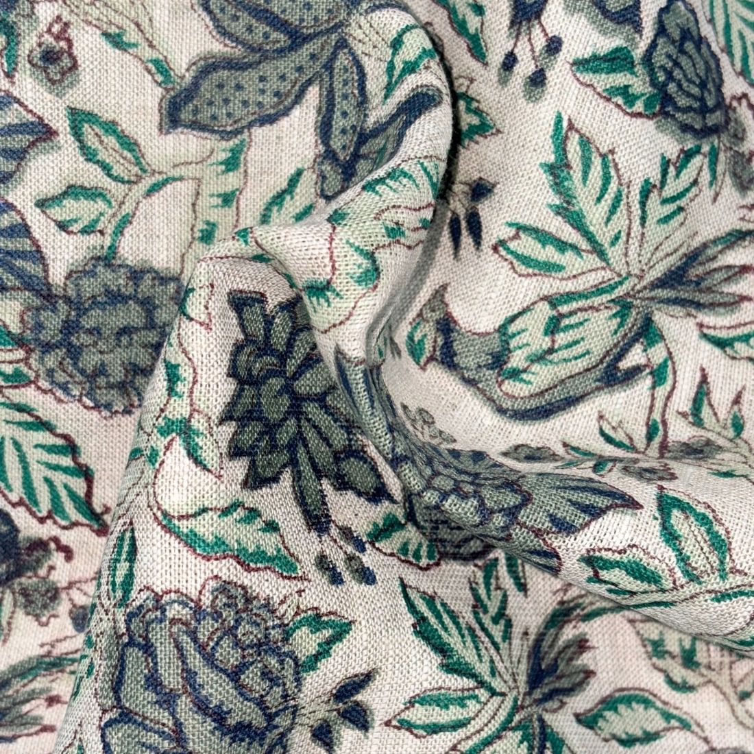 Close-up of fabric with a floral pattern featuring green and blue colors on a grey background.