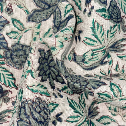 Close-up of fabric with a floral pattern featuring green and blue colors on a grey background.