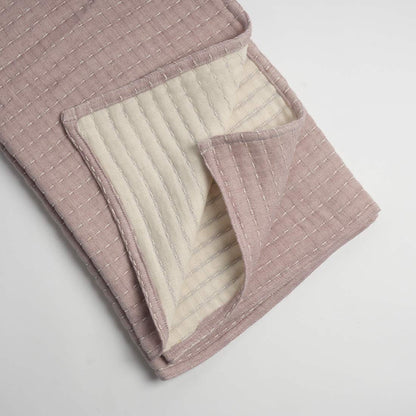 Quilted pink throw with a white interior on a light gray background