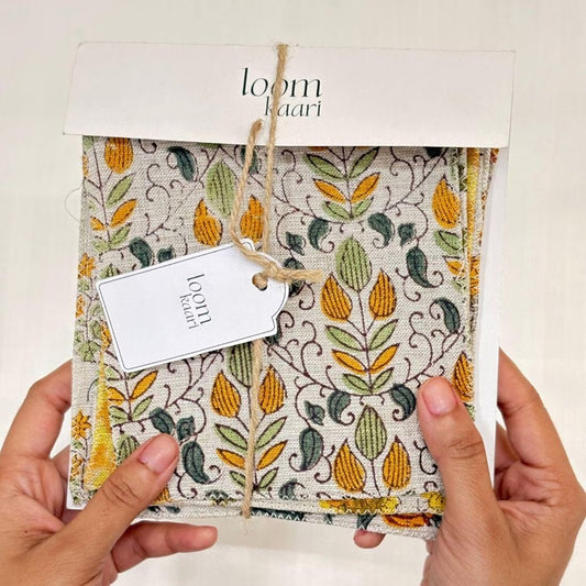A person's hands are holding a swatch set of yellow and green patterned fabrics.