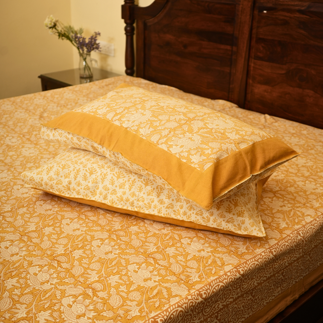 Patterned bedspread with yellow and white design on a bed, featuring a wooden headboard.