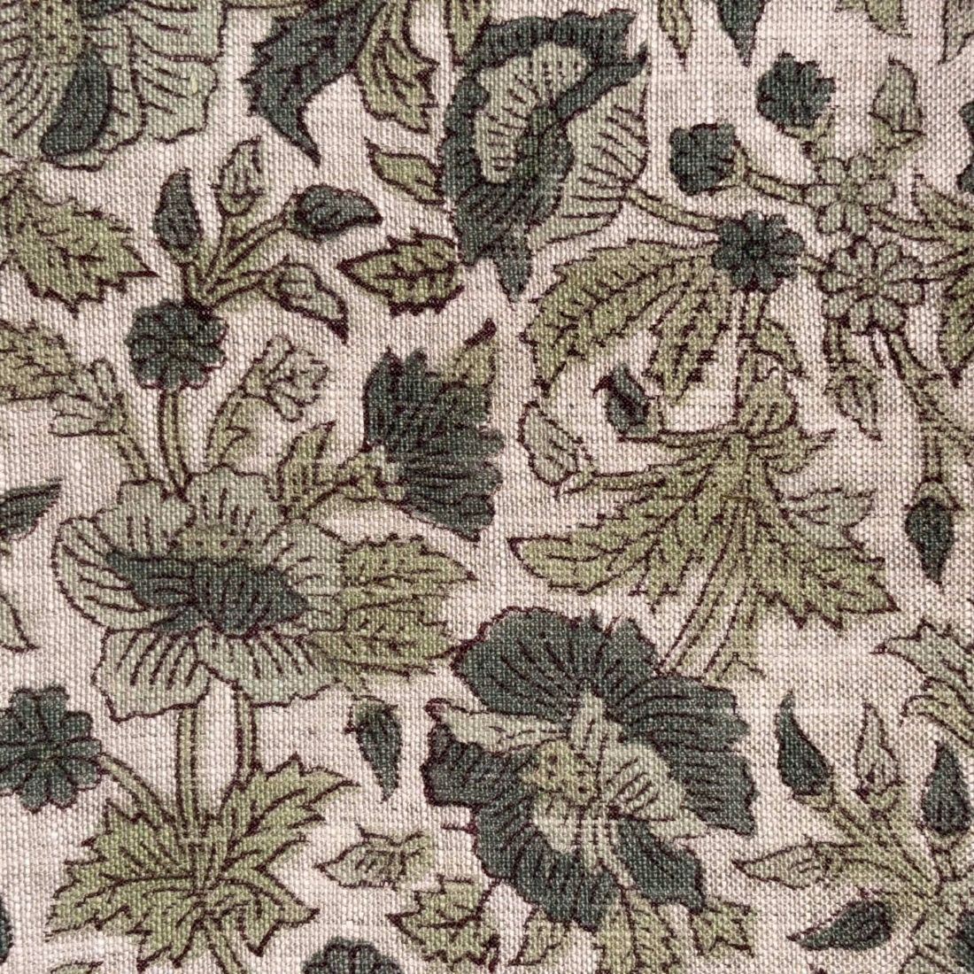 Close-up of floral patterned fabric with green and black leaves on a beige background